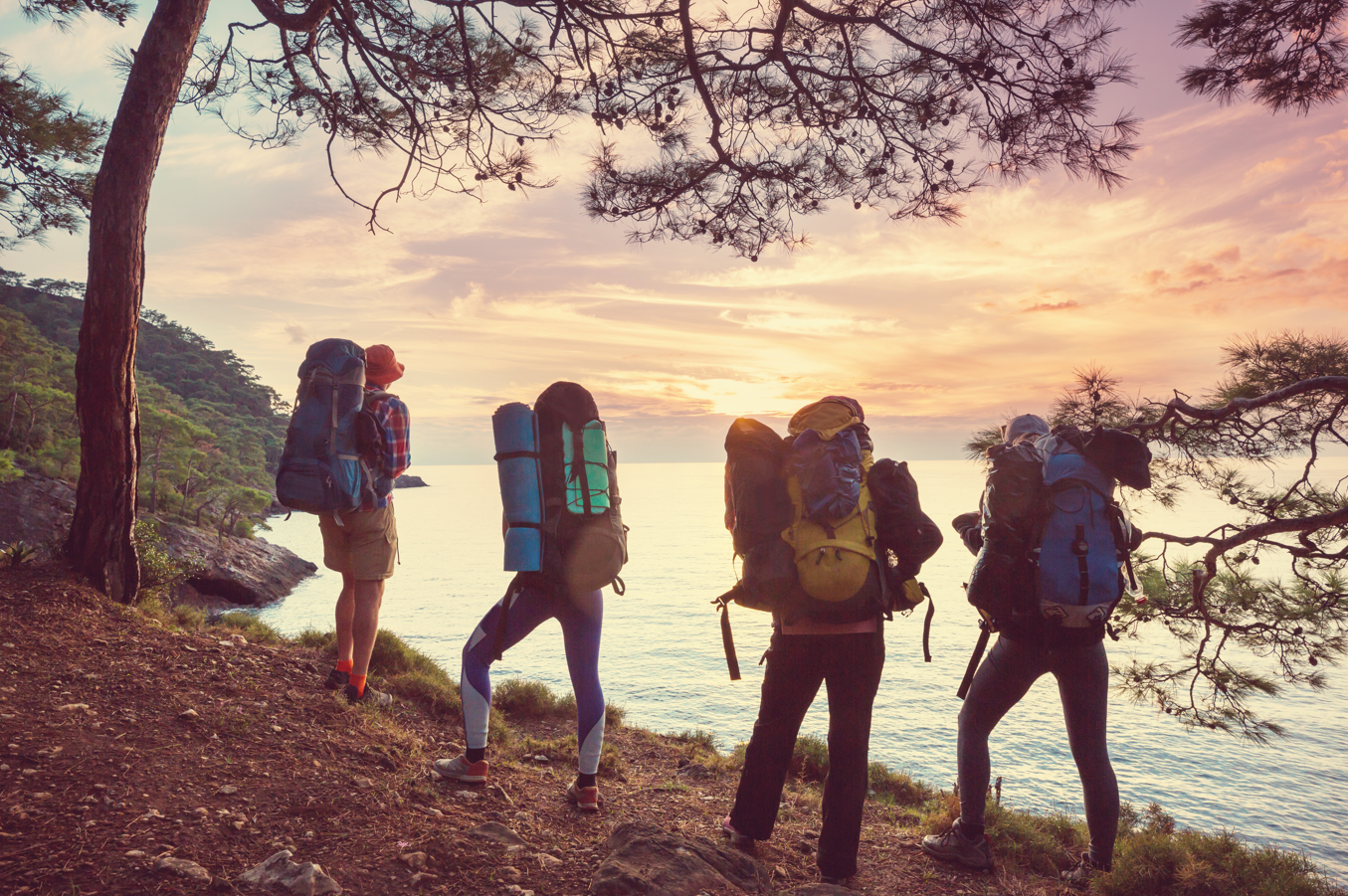 Vier Backpacker wandern an der Küste